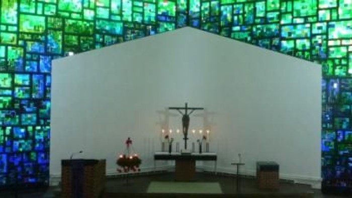Ein Altar in einer Kirche vor einem bunten Glasfenster.