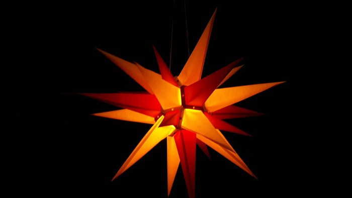 Ein leuchtender, orangefarbener Stern hängt im Dunkeln