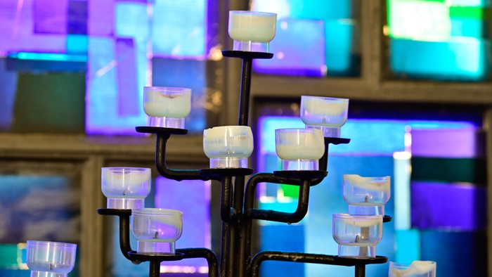 Mehrarmiger Kerzenhalter mit weißen Kerzen vor buntem Hintergrund