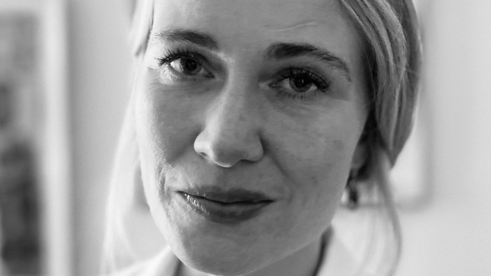 Et sort-hvidt portræt af en kvinde iført en hvid bluse, der kigger direkte på kameraet.