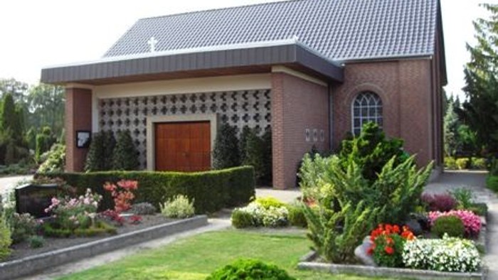 Das Bild zeigt eine Kirche mit einem gepflegten Garten und bunten Blumenbeeten.