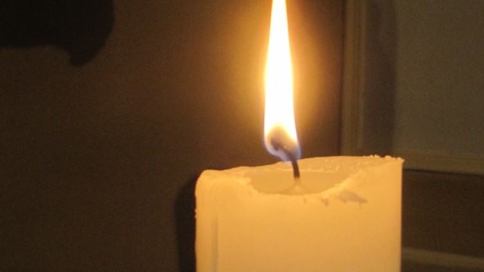 Eine brennende Kerze steht auf einem Tisch.