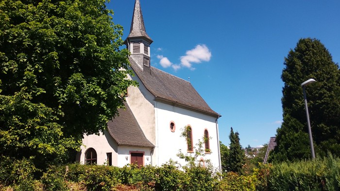 Kleine weiße Kirche mit hohem Turm und grünem Garten