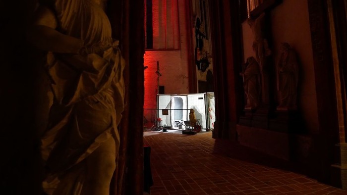 Schwach beleuchteter Raum mit klassischen Statuen und einem kleinen Altar mit Kerzen und religiösen Gegenständen.