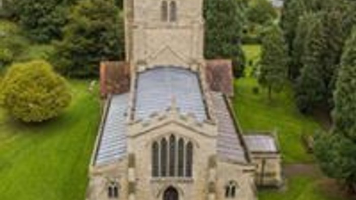 Aerial view of a large church surrounded by greenery.
