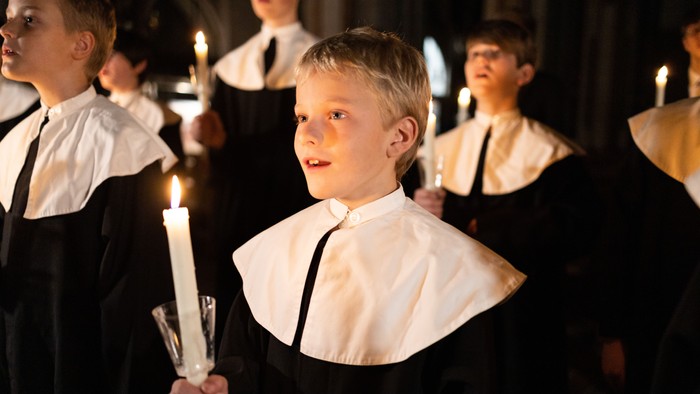 Kinder in schwarzen und weißen Roben halten Kerzen