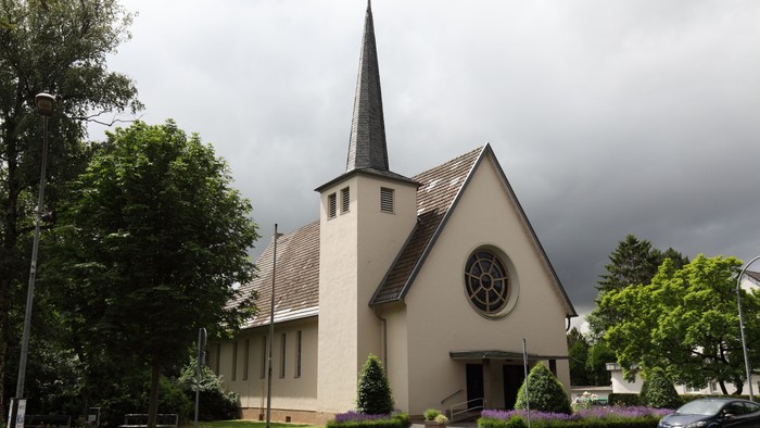 Kleine Kirche mit hohem Turm und Rosengarten vor dem Gebäude