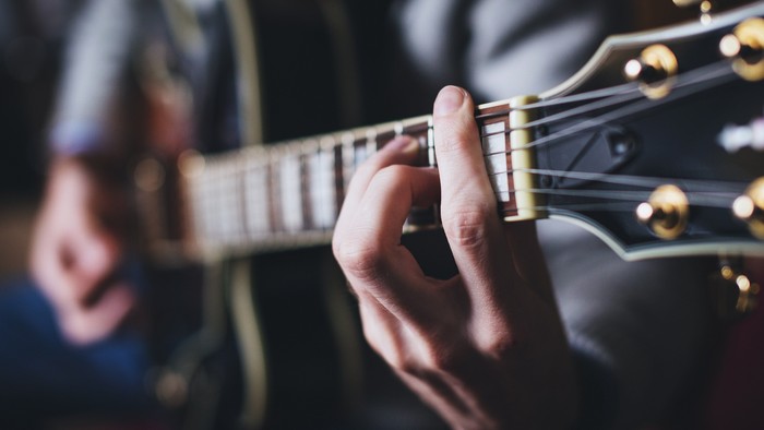 En hånd spiller en gitars trasser.