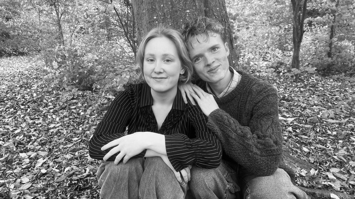 Par, der sidder på jorden i en skov.