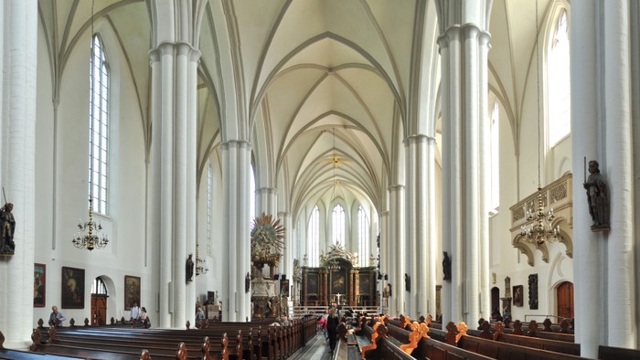 Großzügige Kirchenhalle mit hohen Säulen und zahlreichen Besuchern.
