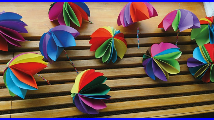 Bunte Papierblumen auf Holzboden.