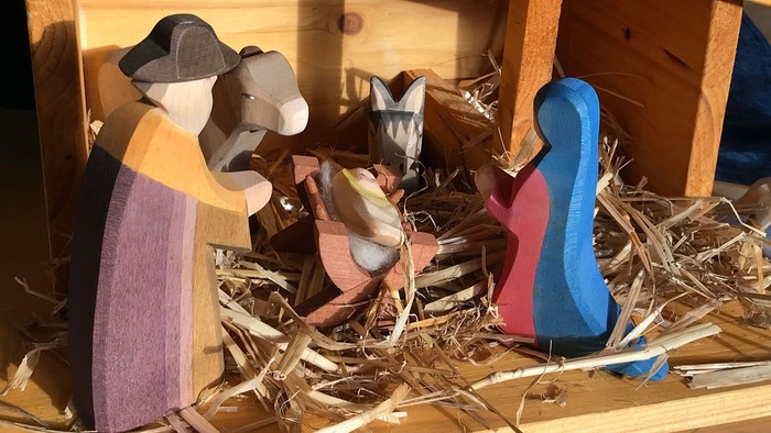 Krippe aus Holz mit Maria, Josef, dem Kind und den Tieren.