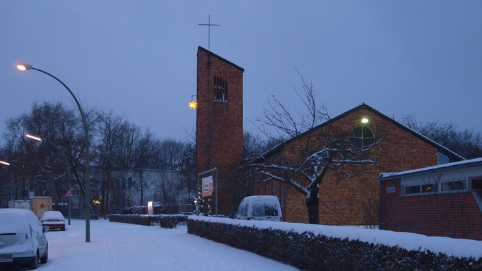 Schneebedeckte Straße mit Kirche und Autos