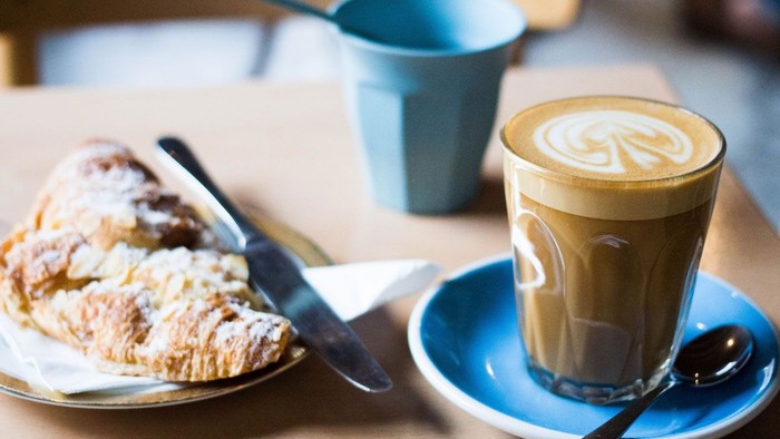 Ein Stück Kuchen, ein Becher Kaffee und eine Tasse Tee auf einem Tisch