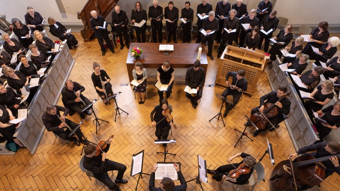 Ein großer Chor und Orchester proben in einem Saal