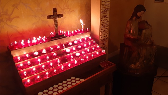 Bunte Kerzen in Kirchenraum mit Marienstatue