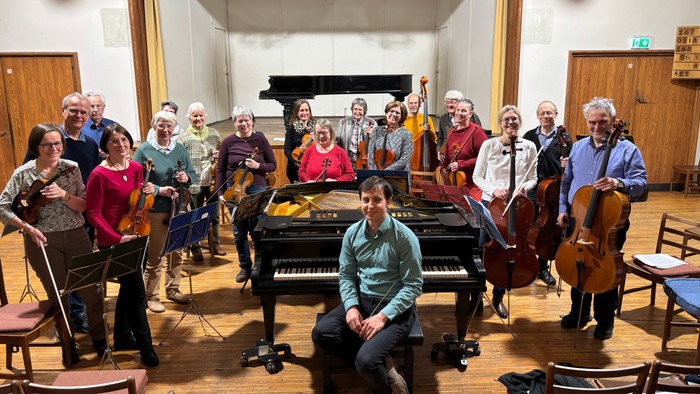 Eine Gruppe von Musikern posiert mit ihren Instrumenten in einem Probenraum