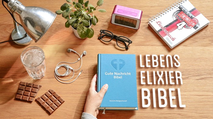 Ein Schreibtisch mit Büchern, Schokolade, einer Pflanze und einem Licht.