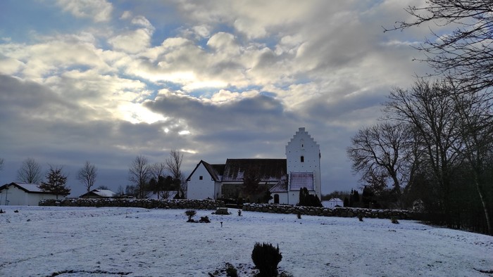 En snedækket mark med et stort hvidt hus i baggrunden