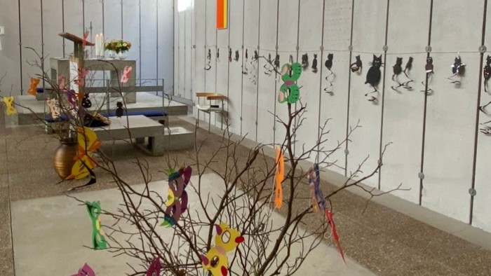 Indenrigsrum med farverige papirfugle og blomsterarrangementer.