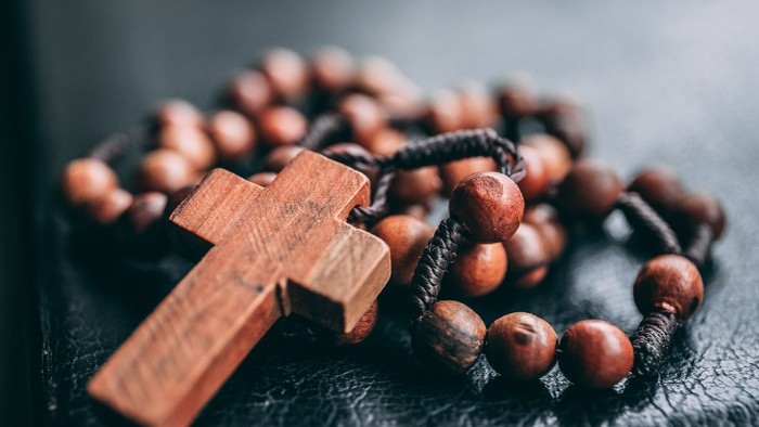 Holzkreuz und Rosenkranz auf schwarzer Oberfläche