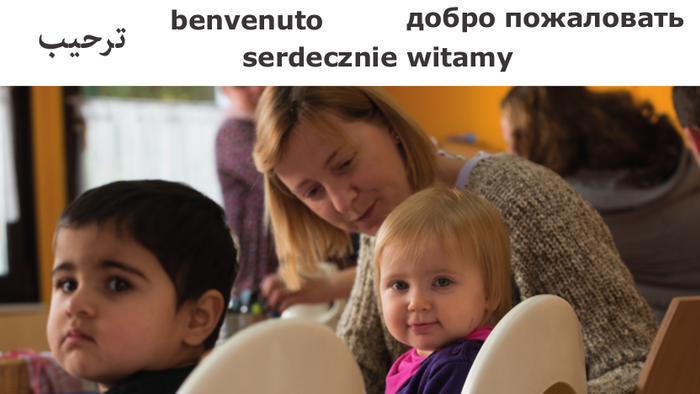 Kinder im Vordergrund mit Frau am Tisch