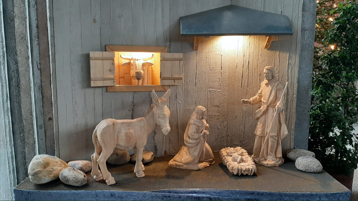 Eine Krippe mit Holzfiguren vor einer Holzwand