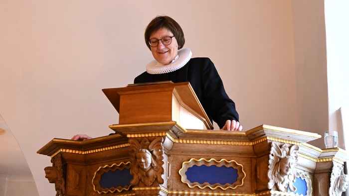 En person, der spiller på et prægtigt træpibeorgel med dekorative blå paneler.