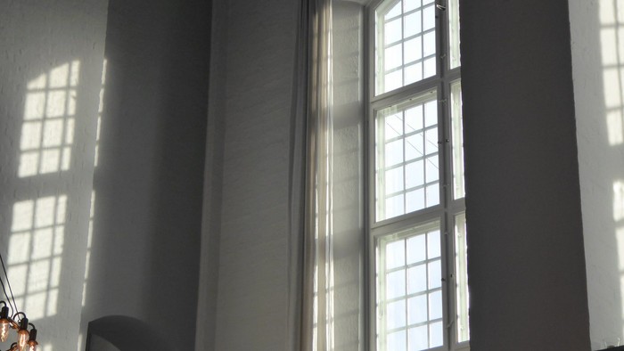 Et rum med store buevinduer og lysende solstråler.