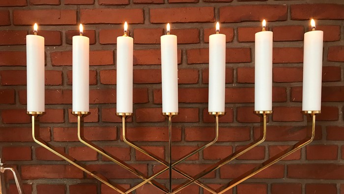 En gylden Menora med ni lysede lygter mod røde mursten.