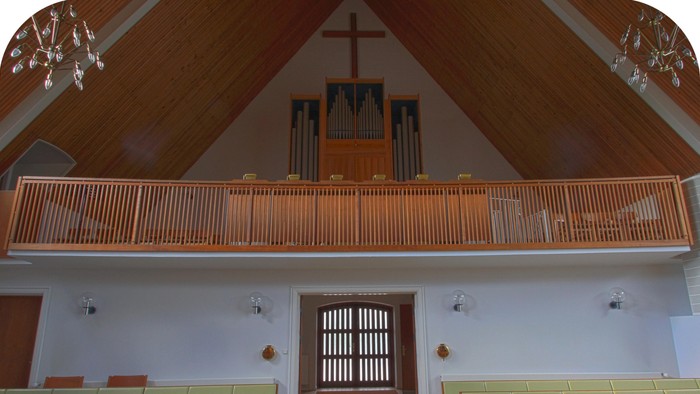 Indenrigs syn på kirke med orgel og alter.