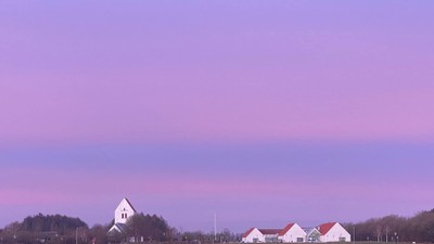 En rødlysende solgang over en åben landskab med en kirke og en gruppe svane.