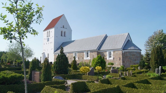En smuk kirke med omgivelser af grønne planter og træer