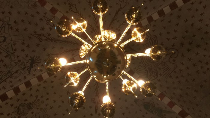 En stor, lyseglødende kroneslynge hænger fra taket.