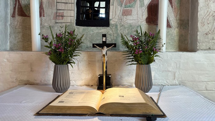 En altertavle med blomsterarrangementer og en åben bog