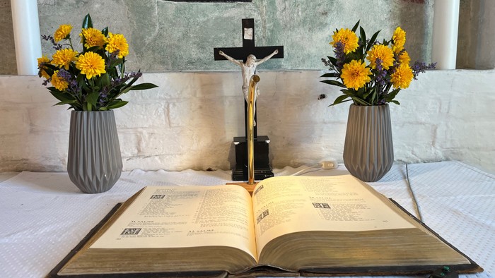 En altertavle med blomsterarrangementer og en åben bog