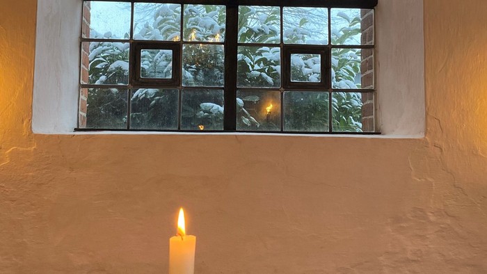 En lille bord med en lystende lyse stå for et vindue.