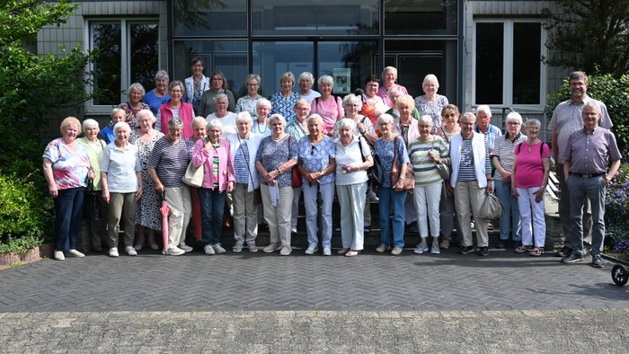 Eine Gruppe älterer Menschen posiert vor einem Gebäude.