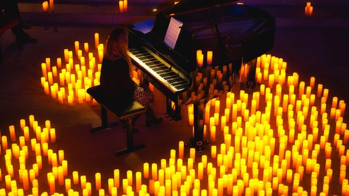 Eine Frau spielt Klavier inmitten von Kerzen.