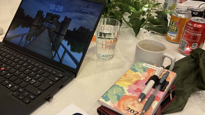 Billede af kontor med laptop, notatblok, og drikkevarer.