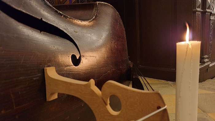 En cello og en lystende lyse stå ved siden af hinanden på en bord.