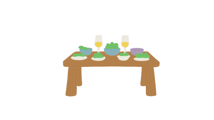 Ein einfacher Holztisch, gedeckt mit Tellern, Schüsseln, Getränken und ein paar bunten Gegenständen.