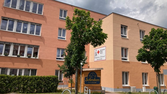 Grosses oranges Gebäude mit vielen Fenstern und Bäumen davor