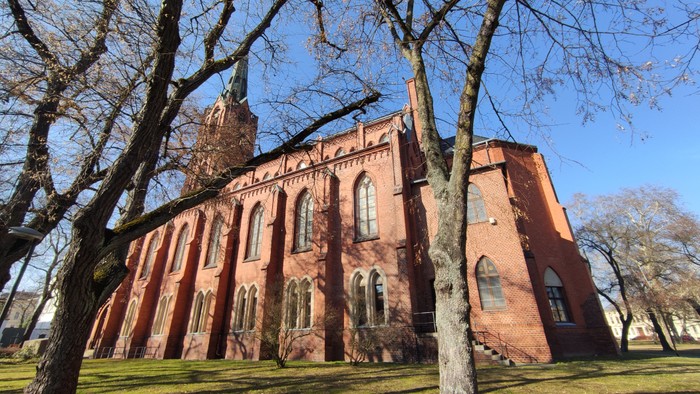 St. Gertraud von der Südostseite aus der Froschperspektive. Gotischer Backsteinbau mit Turm und Spitze.