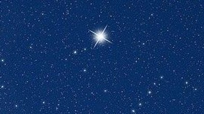 En klar stjerne skinner tydeligt på en klar nattehimmel fyldt med utallige mindre stjerner.