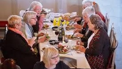 En gruppe mennesker sidder sammen ved et bord og spiser.