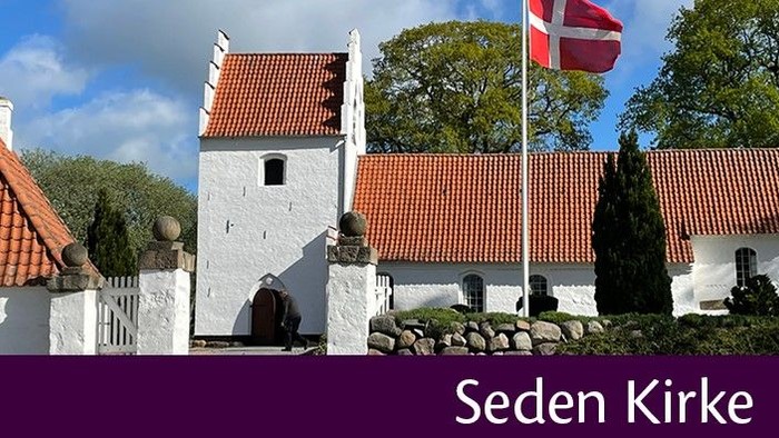 Et hvidt kirkebygning med røde tag og en dansk flag på tårnet