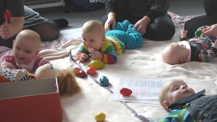 Børn spiller med legetøj på gulv.