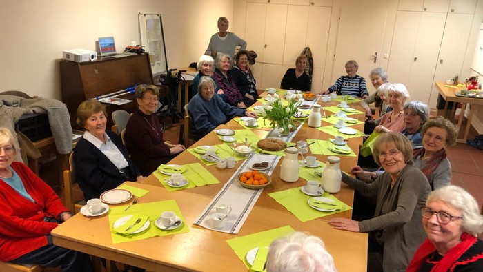Eine Gruppe älterer Menschen sitzt an einem langen Tisch und isst gemeinsam.