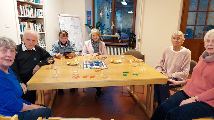 Eine Gruppe älterer Menschen sitzt um einen Tisch und spielt Gesellschaftsspiele.